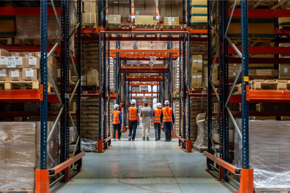 over 100 years of third party logistics - experienced warehouse team walking through large shrink wrapped pallets stored on racking